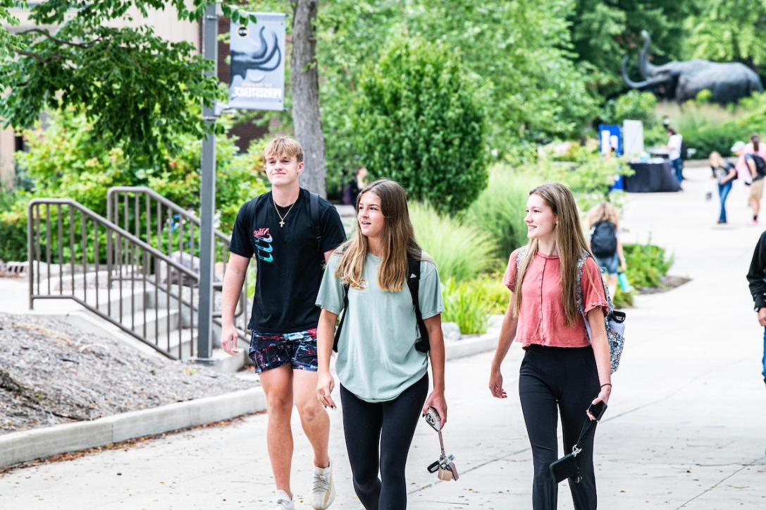 Three students walking across campus to class.